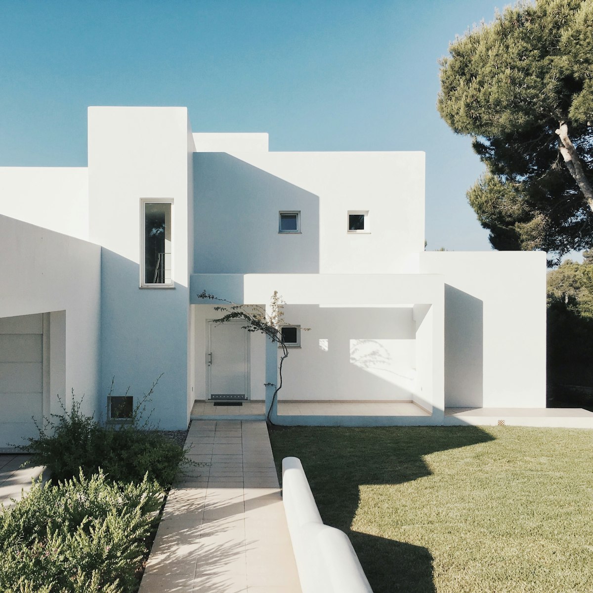 Bright white single-level home with a paved entry path and lawn (stock photo — replace with a real photo of this home).